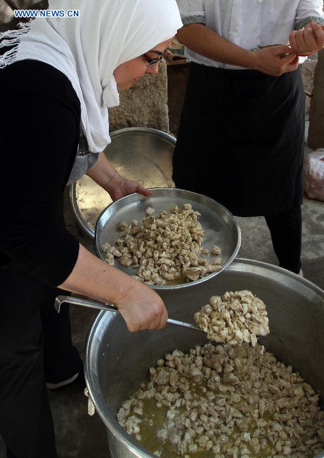 A Syrian volunteer prepares meals to be distributed later to the needy, at a makeshift charity kitchen in Damascus, capital of Syria, July 4, 2014. The meals will be distributed during the Muslims&apos; holy month of Ramadan, during which Muslims abstain from food, drink and sex from sunrise to sunset. Some non-government groups assist those displaced by offering the meals.