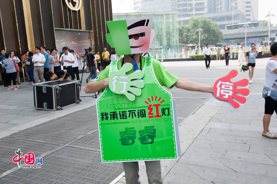 A volunteer traffic warden dressed like a robot, or &apos;transformer,&apos; as he prefers, shows his gagets in directing pedestrians at crossroads with traffic lights. The local government of east Beijing&apos;s Chaoyang District initiates a campaign entitled &apos;I promise not to run a red light&apos; on Tuesday, July 8, 2014, in a bid to eliminate jaywalking in this flourishing part of the Chinese capital. [Photo by Chen Boyuan / China.org.cn]