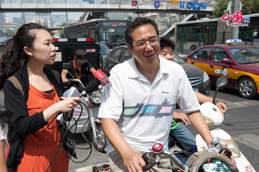 A random cyclist (R) says he has faith in the government&apos;s effort in curbing jaywalking, among other irregularities in traffic in Beijing&apos;s Chaoyang District. The local government of east Beijing&apos;s Chaoyang District initiates a campaign entitled &apos;I promise not to run a red light&apos; on Tuesday, July 8, 2014, in a bid to eliminate jaywalking in this flourishing part of the Chinese capital. [Photo by Chen Boyuan / China.org.cn]