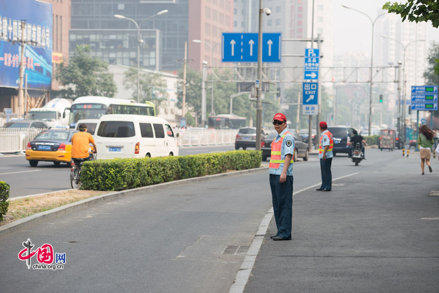 Two traffic wardens direct traffic in a street in east Beijing&apos;s Chaoyang District on Tuesday, July 8, 2014. The local government of east Beijing&apos;s Chaoyang District on this day initiates a campaign entitled &apos;I promise not to run a red light&apos; in a bid to eliminate jaywalking in this flourishing part of the Chinese capital. [Photo by Chen Boyuan / China.org.cn]