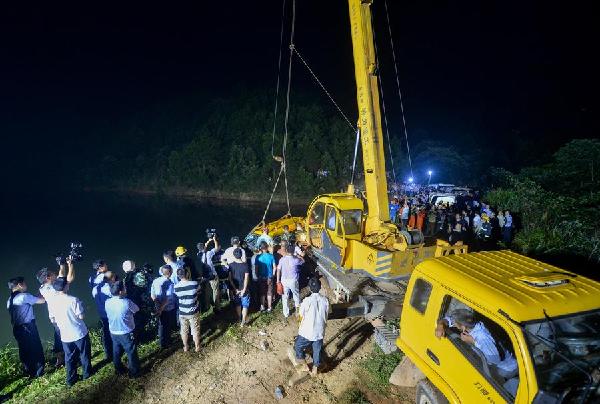 Rescuers try to get a minivan out of water by using a crane in Changsha, Hunan province, July 11, 2014. All 11 people, including eight kindergarten children, died after the minivan fell into a pond Thursday. [Photo/Xinhua] 