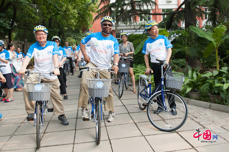 Alain Noudehou (M) poses for photos with Zheng Baotang, the President of Giant Bike (China) and Ma Zhongchao, Chairman of the China Bicycle Association (CBA) on the afternoon of Friday, July 18, 2014 at the UN China compound in Beijing, as Giant Bike officially donates 30 bikes to the UN. [Photo by Chen Boyuan / China.org.cn]