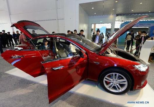 Visitors look at a Tesla vehicle during the 2nd China Shanghai International Technology Fair (CSITF) in east China's Shanghai, April 24, 2014. Tesla Motors is an American company which designs and manufactures electric vehicles. [Xinhua/Lai Xinlin] 