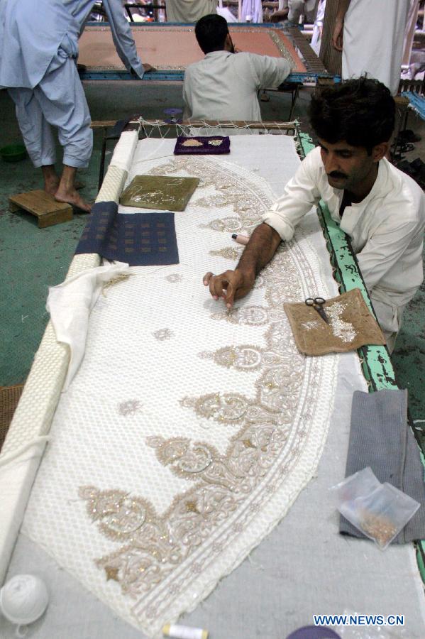 Pakistani workers work on a handmade suit ahead of Eid ul Fitr holiday in northwest Pakistan's Peshawar on July 21, 2014. [Photo/Xinhua]