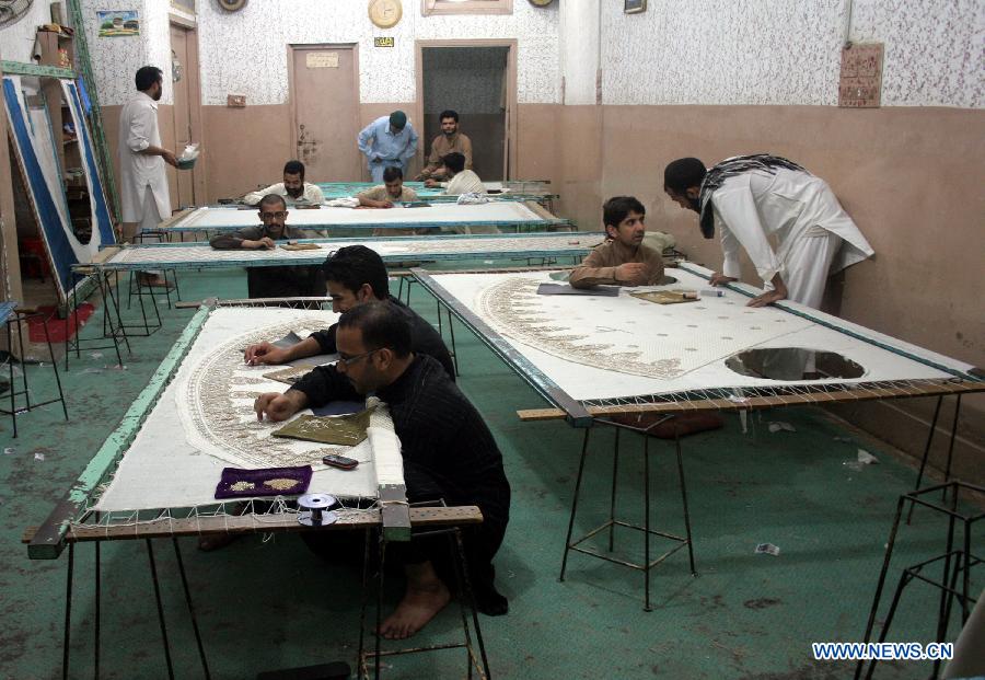 Pakistani workers work on a handmade suit ahead of Eid ul Fitr holiday in northwest Pakistan's Peshawar on July 21, 2014. [Photo/Xinhua]