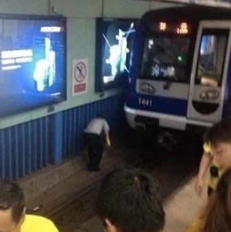 Workers cleaning up the mess after one woman jumped into the rail ditch and got killed at Guloudajie Station of Line 2 on Wednesday morning, July 23, 2014. [Photo / Beijingtimes]