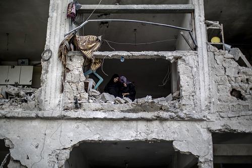 Palestinian women console themselves while inspecting the damages inside their destroyed home in the northern district of Beit Hanun in the Gaza Strip during an humanitarian truce, on July 26, 2014. [Xinhua photo]
