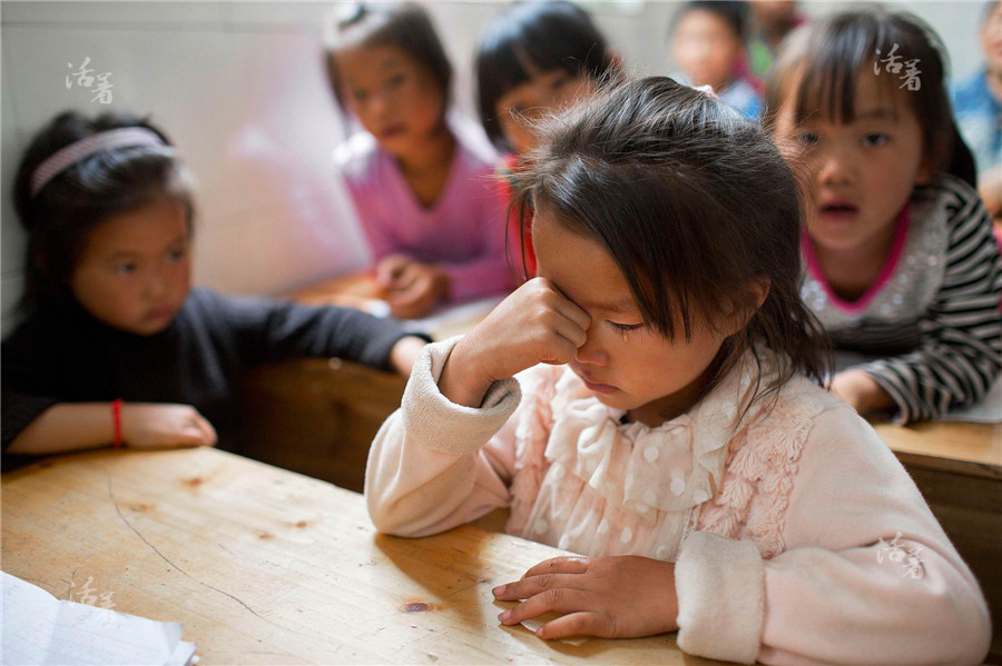 Ma Shaoye, a kindergarten girl, has a headache. She pinches her nose to ease the pain. For lack of medicine in the area, the students simply suffer from and tolerate small diseases. [Photo/qq.com]