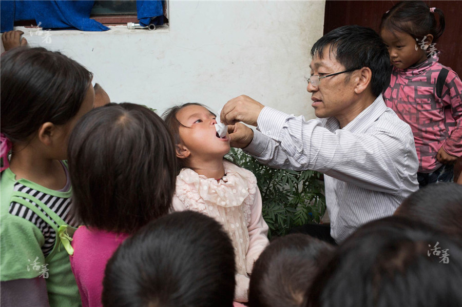 During the break, Xiong Chaogui feeds Ma Shaoye with a kind of “fever-abating powder”. Without the contact information of the parents, Xiong has to relieve the pain with a simple treatment. For the left-behind children, the school bears great risk in taking daily care of them. [Photo/qq.com]