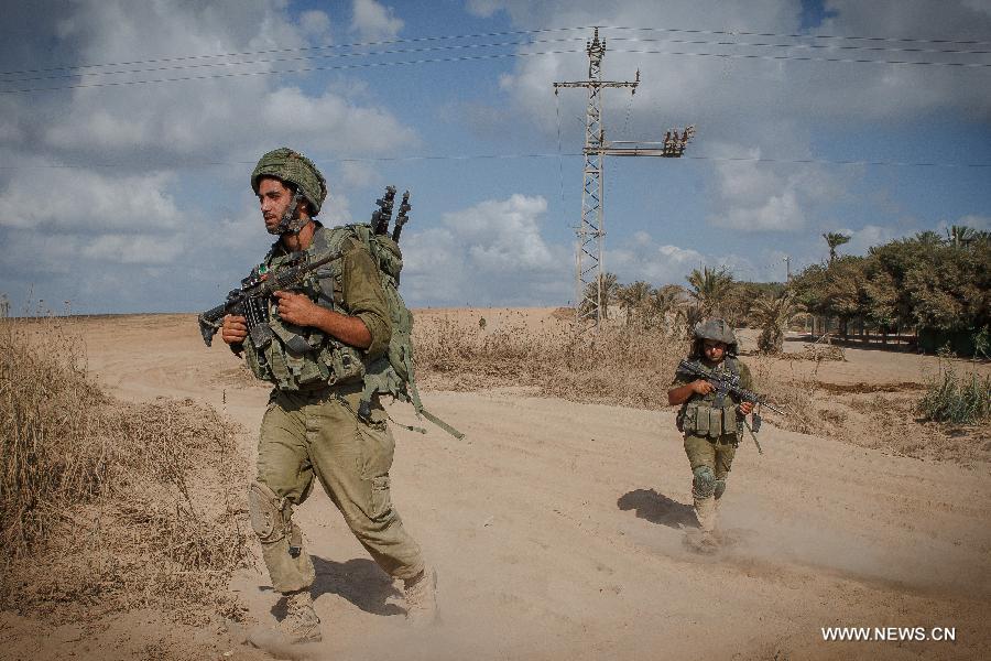 Israeli soldiers walk in southern Israel bordering the Gaza Strip as they return from Gaza, on Aug. 4, 2014. The Israeli military said Tuesday morning it has pulled back all of its ground forces from the Gaza Strip, as a three-day truce between Israel and Hamas went into effect. [Photo/Xinhua]