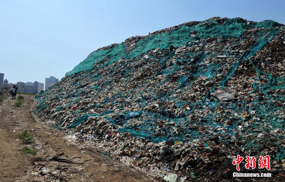 Photo taken on August 7, 2014 shows a 30 metres high garbage mountain at the crossroad of Huanghe avenue and Zhufeng street of Shijiazhuang, central China's Hebei province. The garbage mountain has been piled up as high as a 9-story Building in the last 30 years. The local village committee now is dealing with these wastes. [Photo: Chinanews.com] 