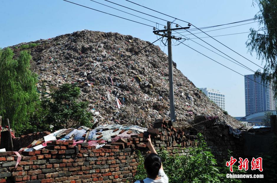 Photo taken on August 7, 2014 shows a 30 metres high garbage mountain at the crossroad of Huanghe avenue and Zhufeng street of Shijiazhuang, central China's Hebei province. The garbage mountain has been piled up as high as a 9-story Building in the last 30 years. The local village committee now is dealing with these wastes. [Photo: Chinanews.com]