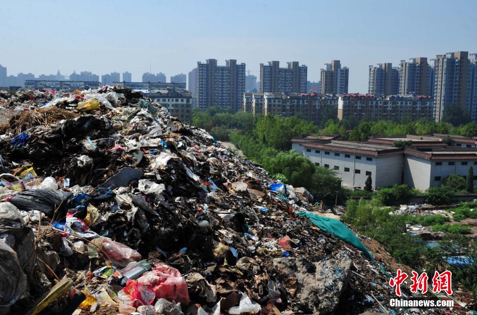 Photo taken on August 7, 2014 shows a 30 metres high garbage mountain at the crossroad of Huanghe avenue and Zhufeng street of Shijiazhuang, central China's Hebei province. The garbage mountain has been piled up as high as a 9-story Building in the last 30 years. The local village committee now is dealing with these wastes. [Photo: Chinanews.com]