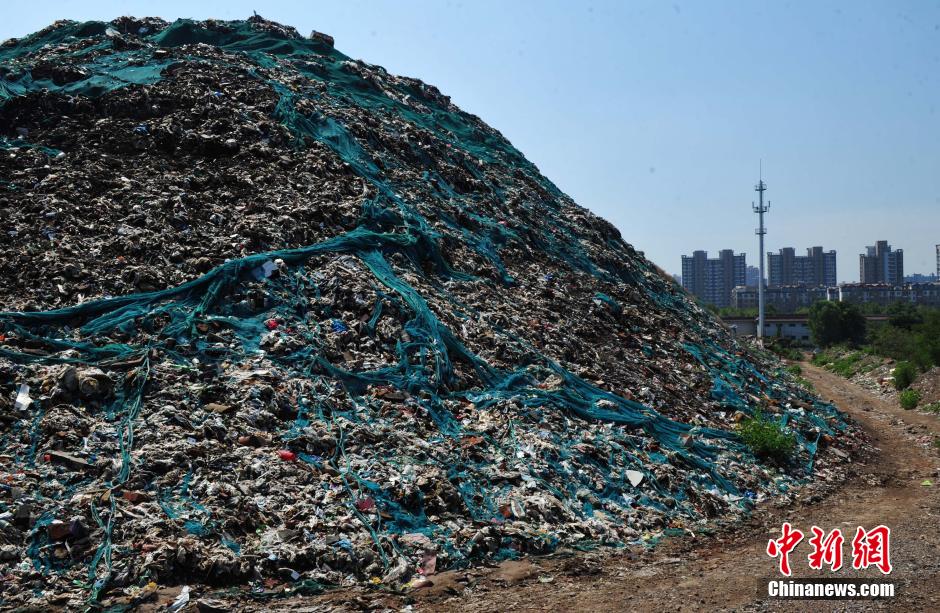 Photo taken on August 7, 2014 shows a 30 metres high garbage mountain at the crossroad of Huanghe avenue and Zhufeng street of Shijiazhuang, central China's Hebei province. The garbage mountain has been piled up as high as a 9-story Building in the last 30 years. The local village committee now is dealing with these wastes. [Photo: Chinanews.com]