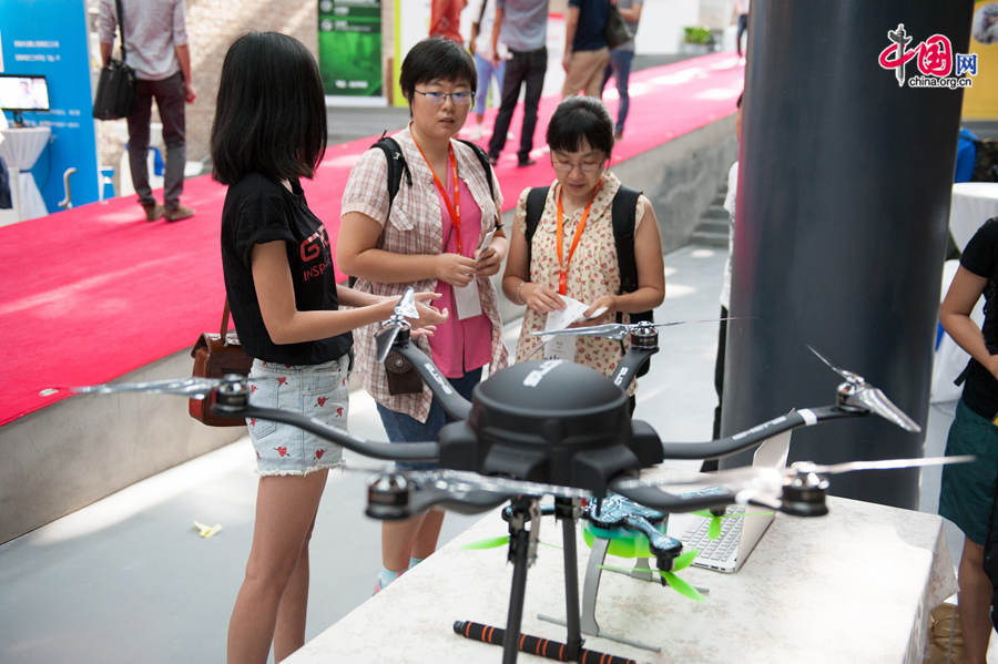 Attendants to the TechCrunch 2014 ask about a radio controlled flying quadcopter helicopter on Monday, Aug. 11, 2014 in Beijing. The TechCrunch 2014 will last two days during which science and technology companies will showcase their latest products as well as solutions. [Photo by Chen Boyuan / China.org.cn]