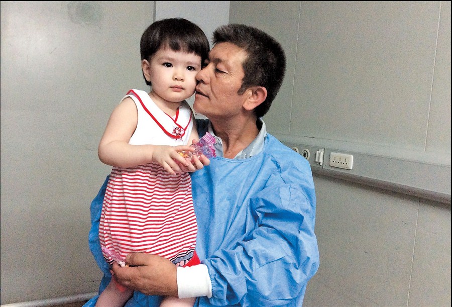 Yakupu Aji holds his granddaughter, known as Alimu, yesterday at the Shanghai Children’s Hospital, where she has lived for two and a half years. — Ti Gong