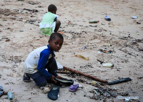Children play on the beach nearby a ferry port linking the Lungi International Airport and the downtown of Freetown, capital of Sierra Leone, on Aug. 14, 2014. [Xinhua]