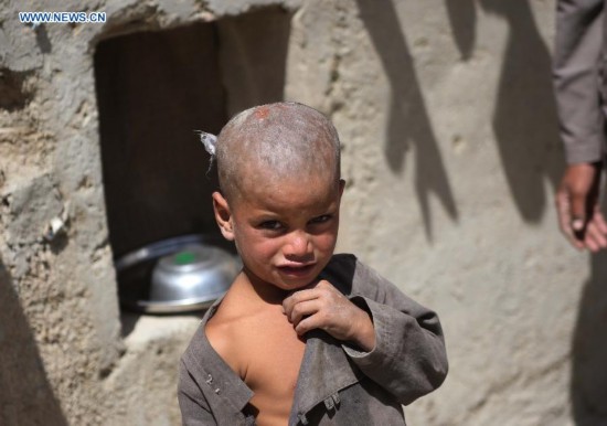 An Afghan child stands outside a tent at a displaced camp in Kabul, Afghanistan on Aug. 21, 2014. [Photo/Xinhua]