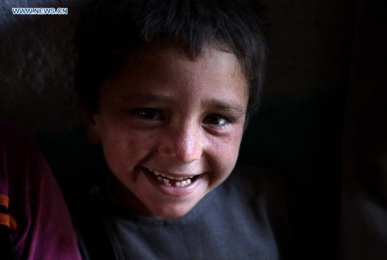 An Afghan child smiles inside a tent at a displaced camp in Kabul, Afghanistan on Aug. 21, 2014. [Photo/Xinhua]