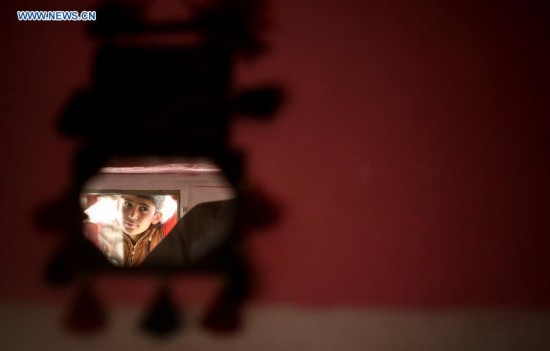 An Afghan child is reflected in a mirror in a tent at a displaced camp in Kabul, Afghanistan on Aug.21, 2014. [Photo/Xinhua]