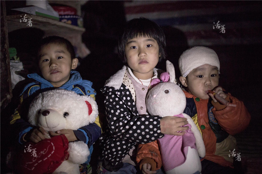 Three-year-old Xiao Bao (right) with his 8-year-old sister Xiao Rong and 5-year-old brother Xiao Cheng at their home in Southwestern China’s Guizhou province. Their mother left them behind in June 2013. [Photo/qq.com]