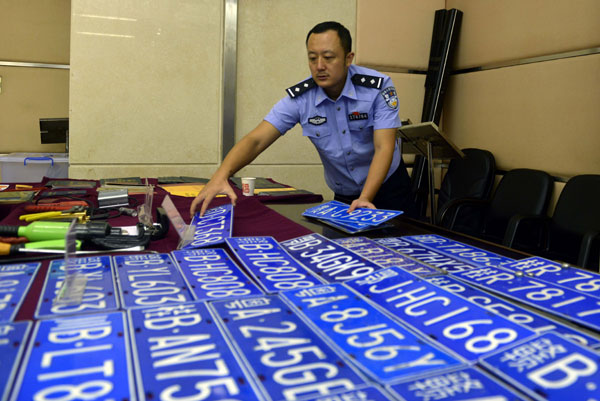 A police officer shows the fake license plates confiscated during a crackdown campaign by public security authorities in Guangdong province at a news conference on Tuesday. Liang Guanhua / For China Daily