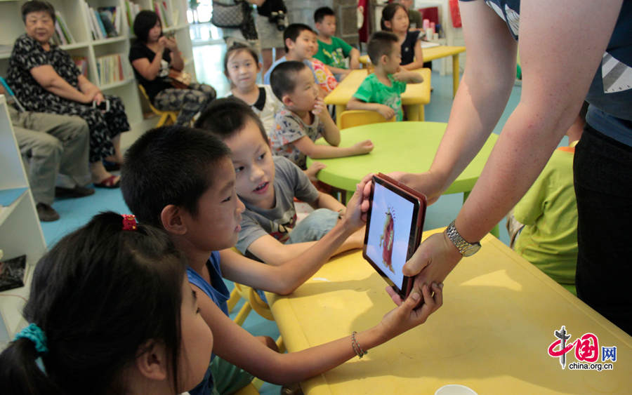 Children look at the images of monsters designed by Endre Skandfer in his Ipad. [Photo by Li Shen/China.org.cn] 