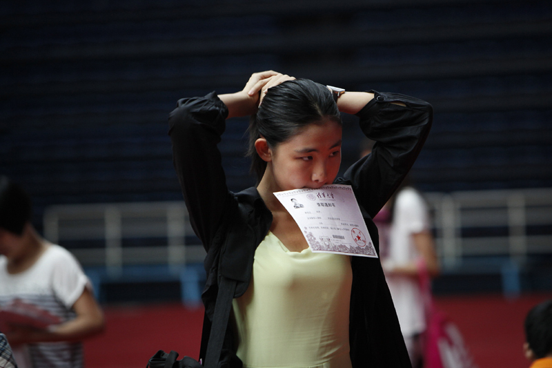 A freshman bundles her hair before posing for her identification photo. [Photo by Kuang Linhua/Asianewsphoto] 