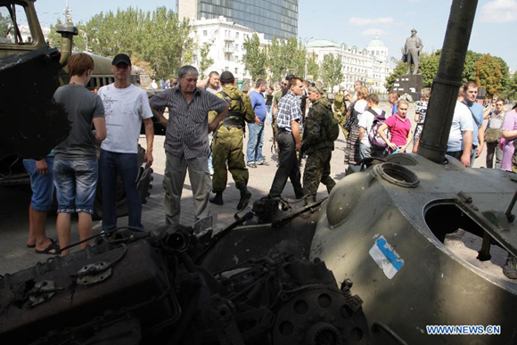 Local people view damaged Ukrainian army armored vehicles in Donetsk, Ukraine, on Aug. 24, 2014. Local militia in Donetsk held their own parade on the Independence Day of Ukraine. [Photo/Xinhua]