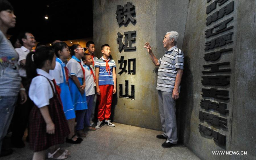 Wang Wenyi (1st R), a surviving forced miner who worked for Japan during the World War II, serves as voluntary visitor guide at a museum of Liaoyuan miners' tomb during Japanese occupation in Liaoyuan, Northeast China's Jilin province, Aug 28, 2014. 