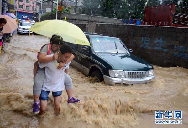 Residents cross a flooded street after heavy rain in Wuxi County, southwest China's Chongqing Municipality, Sept. 1, 2014. [Photo/Xinhua]
