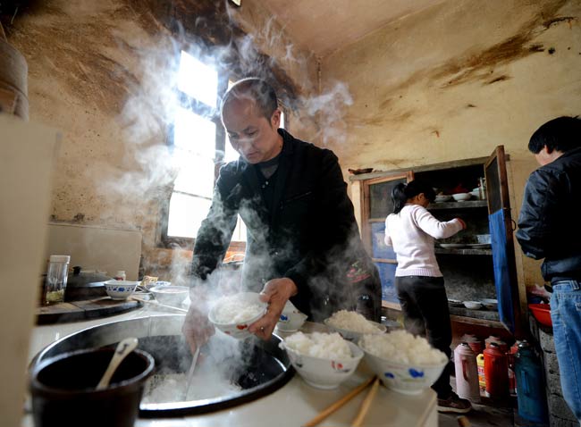 Zhang Gaoping, who was wrongly convicted of rape and murder in 2004 by a court in Zhejiang and jailed for 10 years with his nephew, prepares a meal for his family after being released. ZHANG RUI / XINHUA 