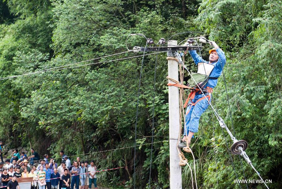 An electritian repairs a power line at a landslide site in Changsheng Village of Changshou District in southwest China's Chongqing, Sept. 14, 2014. Downpours are wreaking havoc in southwest China Saturday. Landslides triggered by continuous rainfalls have killed at least three people here and more buried are yet to be found. (Xinhua/Liu Chan)