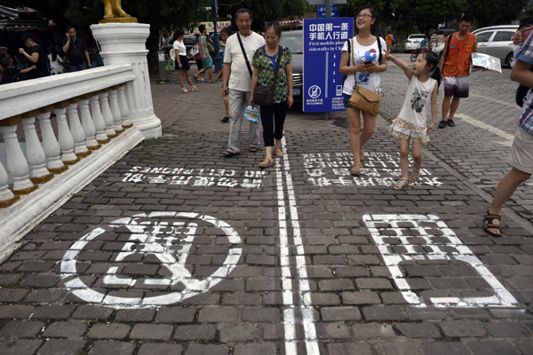 People walk on a sidewalk that is divided into two sections - one for those using cell phones, and the other for those who are not - in Chongqing on Saturday. Ran Wen / for China Daily 