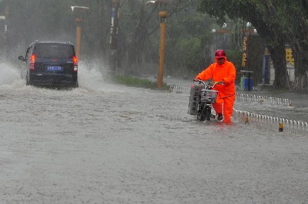 A sanitary worker wades through water on the street in Haikou, Hainan province after typhoon Kalmaegi landed in Wenchang city of the island province at 9:40 am on Tuesday. [Photo/Xinhua] 