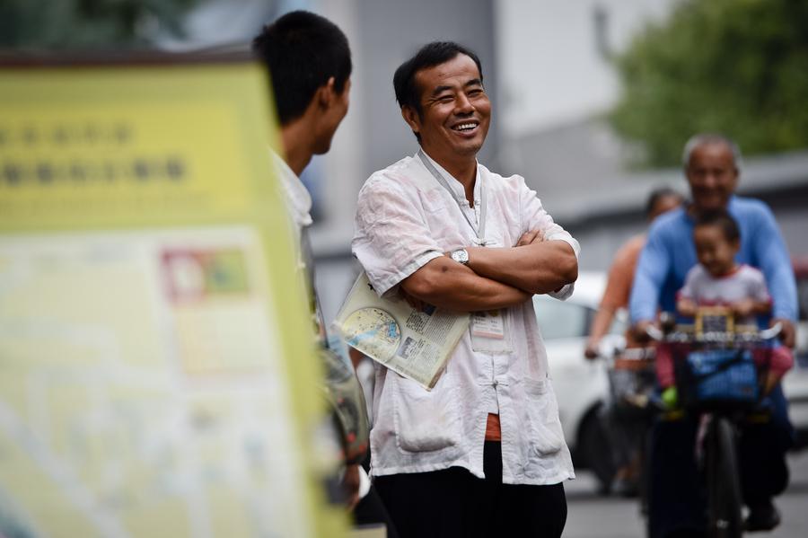 Cao Junlai in a conversation with another rickshaw driver at Shichahai area of Beijing, Sept 12, 2014. [Photo/Xinhua] 