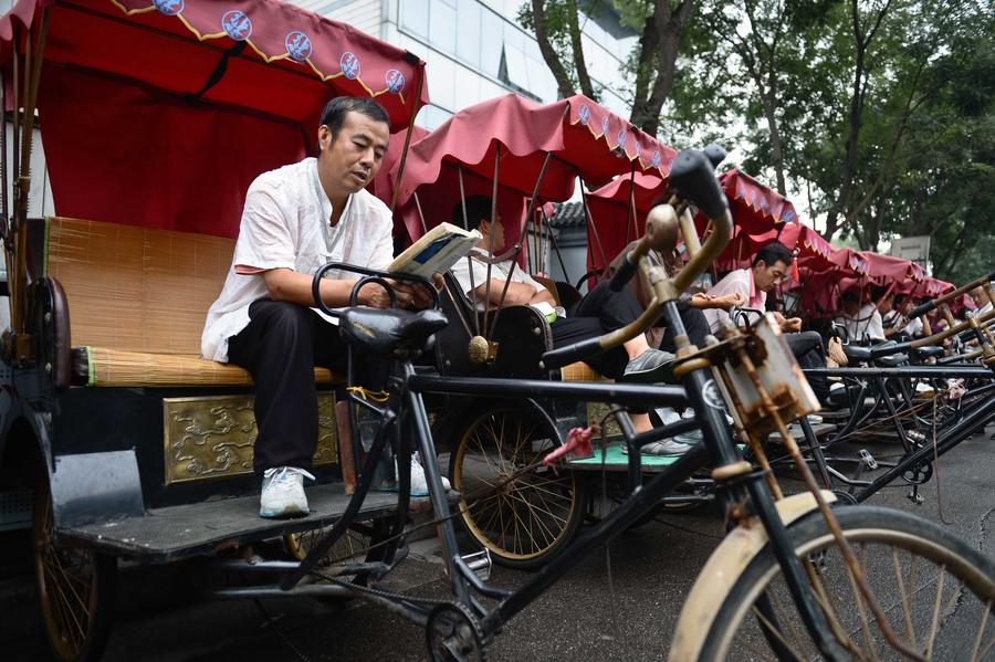 Cao Junlai tells hutong stories to tourists on his rickshaw in Beijing, Sept 12, 2014. [Photo/Xinhua]
