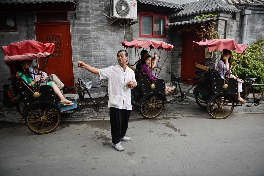 Cao Junlai introduces hutong culture to tourists in Beijing, Sept 12, 2014. [Photo/Xinhua]