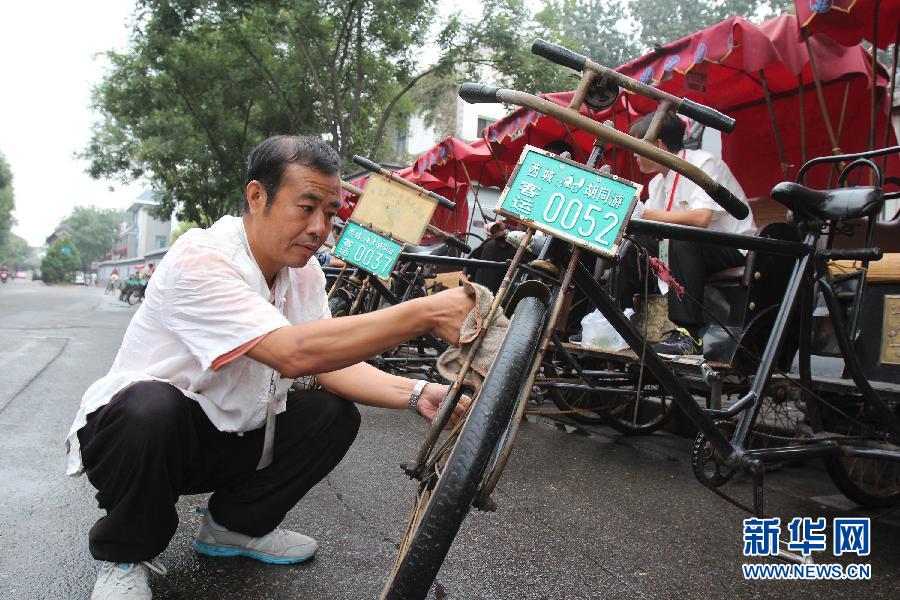 Cao Junlai cleans his rickshaw, Sept 12, 2014. [Photo/Xinhua]