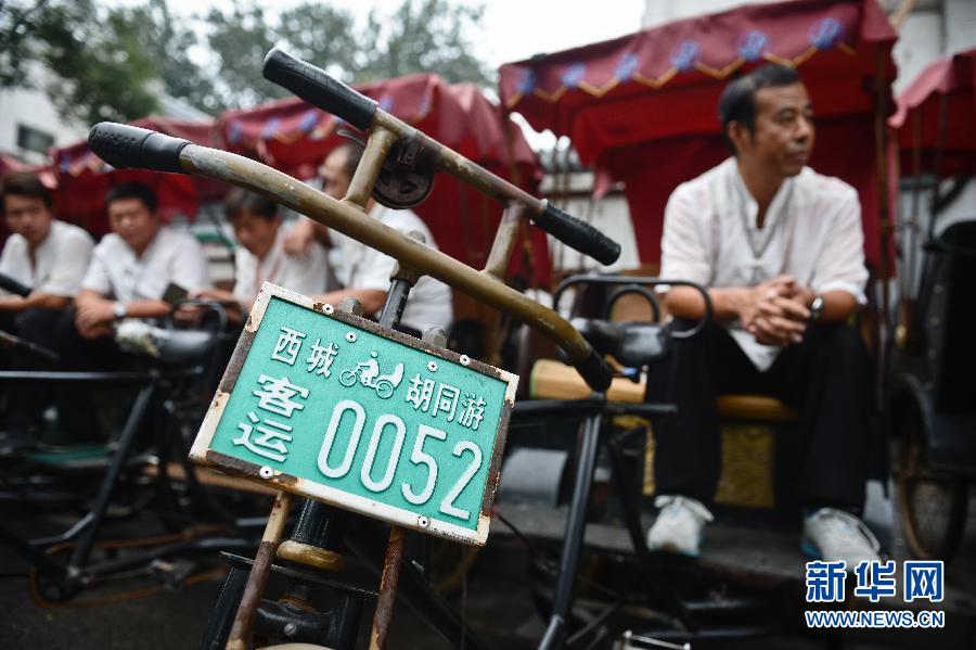 Cao Junlai waits for passengers on his rickshaw, numbered 0052, in Beijing’s Xicheng district, Sept 12, 2014. [Photo/Xinhua]