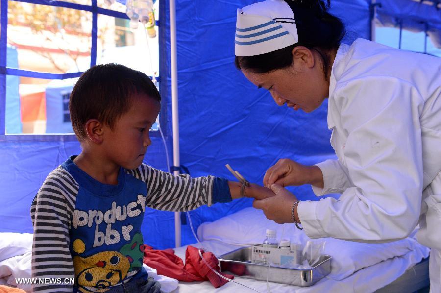 A kid takes an injection at a temporary medical center organized by the 2nd Renmin Hospital of Jinggu County, southwest China&apos;s Yunnan Province, Oct. 8, 2014. One person died and 324 others were injured after a 6.6-magnitude quake jolted Yunnan Province Tuesday night, according to local government. Injured villagers have been sent for medical treatment. 