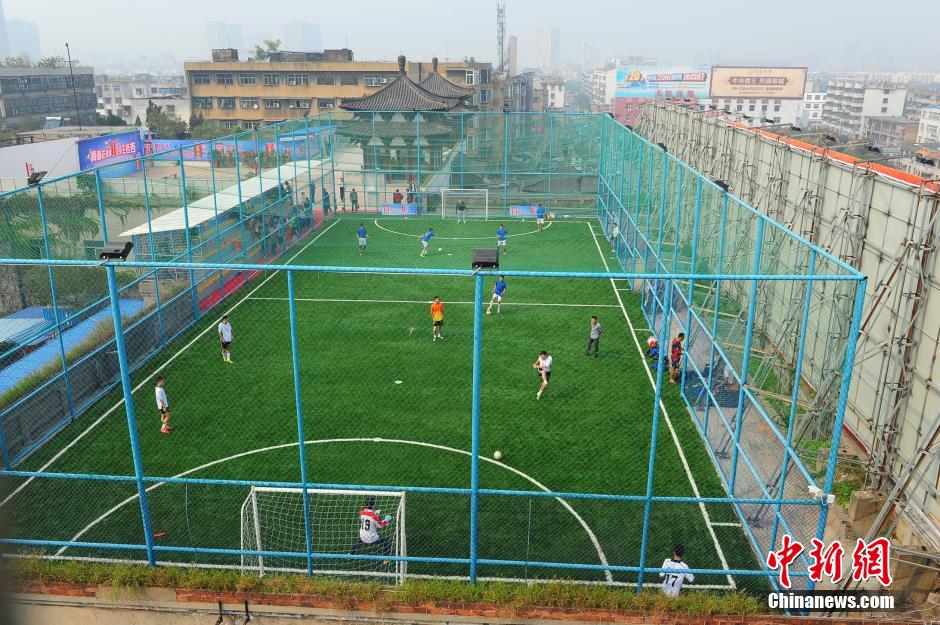 Photo taken shows people playing football at a 'football field in the air' built on the roof of a hall in Fuyang, E China’s Anhui Province on October 12, 2014. Recently, the first 2,000-square meter 'football field in the air' in Fuyang appeared at the roof of a 20-meter-high building, attracting people’s attention. (Photo by Wang Biao)