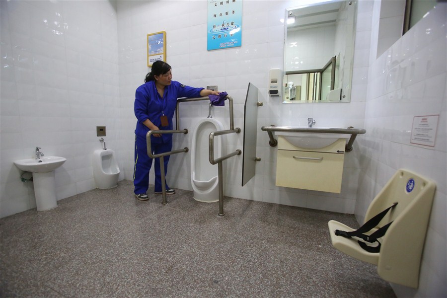 A janitor cleans the facilities at a unisex toilet on Yan'an Road yesterday, one of the city's first. — Wang Rongjiang 