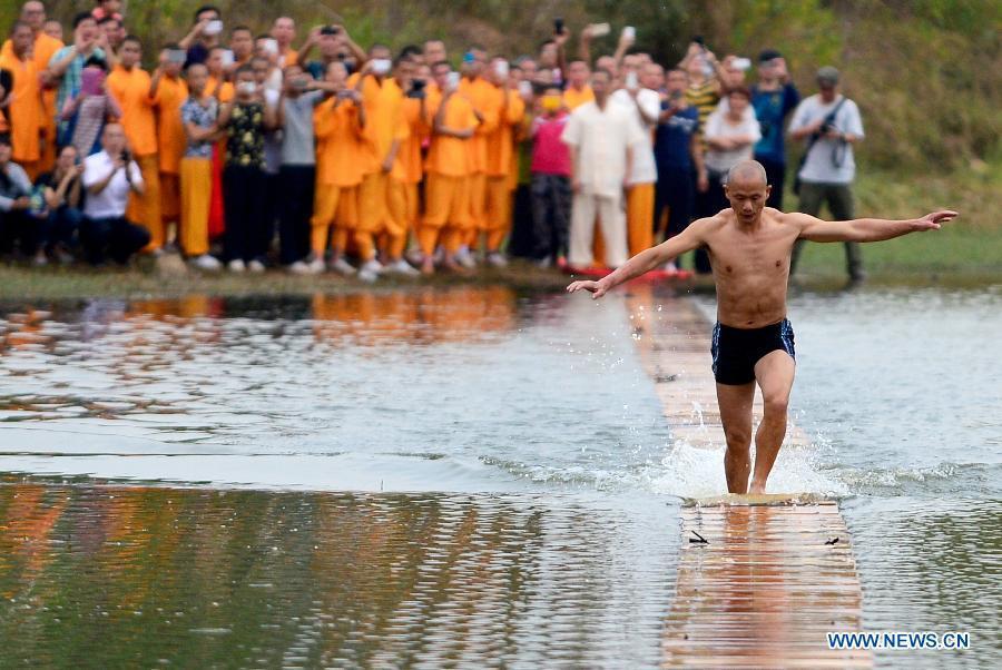 Shi Liliang, a monk from the Quanzhou Shaolin Temple, performs a Chinese martial art stunt by running on water under thin plywood for about 118 meters in Quanzhou City, southeast China's Fujian Province, Oct. 26, 2014. [Xinhua]