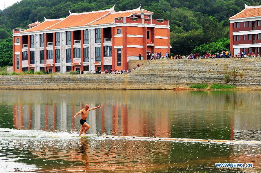 Shi Liliang, a monk from the Quanzhou Shaolin Temple, performs a Chinese martial art stunt by running on water under thin plywood for about 118 meters in Quanzhou City, southeast China's Fujian Province, Oct. 26, 2014. [Xinhua]