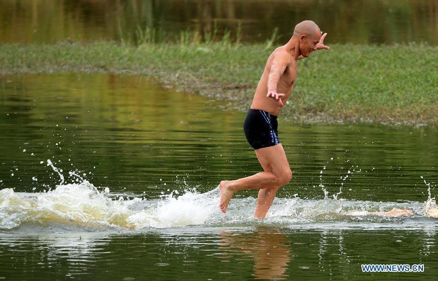 Shi Liliang, a monk from the Quanzhou Shaolin Temple, performs a Chinese martial art stunt by running on water under thin plywood for about 118 meters in Quanzhou City, southeast China's Fujian Province, Oct. 26, 2014. [Xinhua]