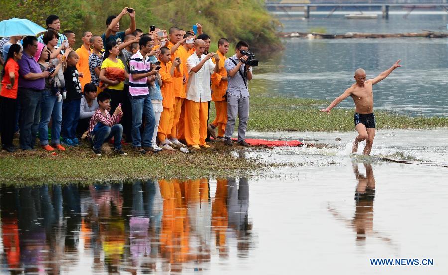 Shi Liliang, a monk from the Quanzhou Shaolin Temple, performs a Chinese martial art stunt by running on water under thin plywood for about 118 meters in Quanzhou City, southeast China's Fujian Province, Oct. 26, 2014. [Xinhua]