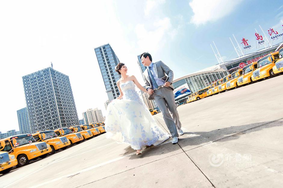  24-year-old Zhang Fan and her husband Wang Gaoming pose for a wedding photo with school buses forming the backdrop. [Photo: iqilu.com]