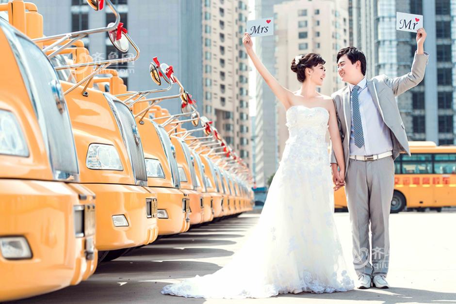 24-year-old Zhang Fan and her husband Wang Gaoming pose for a wedding photo with school buses forming the backdrop. [Photo: iqilu.com] 