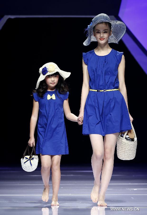 An adult and a child model present creations designed by Dong Wenmei during China Fashion Week in Beijing, capital of China, Oct. 29, 2014. [Xinhua]